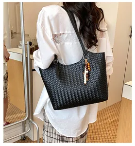 Borsa a spalla nera intrecciata con ciondolo di perline, elegante accessorio moda quotidiano.