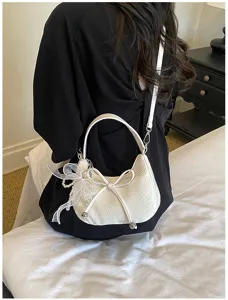 Detailed view of the white woven crescent shoulder bag with cute bow and pearl pendant.