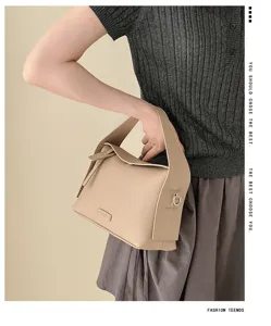 Minimalist beige leather crossbody handbag showcasing delicate texture and metal ring detail.
