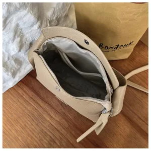 Detailed view of the beige leather crossbody bag interior, showing quality lining and zipper.