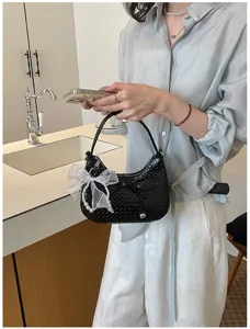 French woven crescent shoulder bag with pearl bow pendant, elegant chic underarm style.