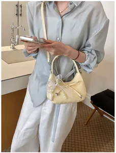 Chic woven crescent shoulder bag detail, elegant pearl and ribbon bow charm, premium daily style.