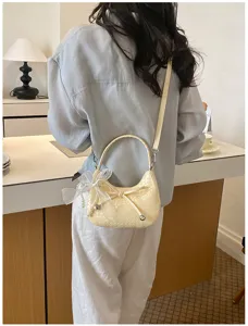 Detailed view of the elegant woven crescent shoulder bag with cute pearl and bow charm.