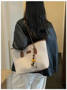 Détail de sac cabas tressé avec tissu beige, poignées en cuir marron et charme quotidien.