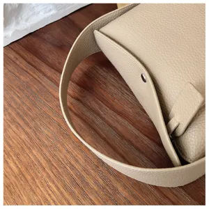 Detailed close-up of women minimalist pebble leather shoulder bag featuring wide strap.