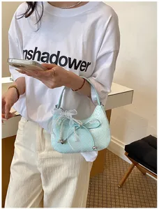 Detailed view of the light blue woven crescent shoulder bag with chic bow and pearl charms.