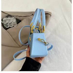 Dettaglio in primo piano della elegante borsa a mano mini azzurro chiaro con dettagli dorati.