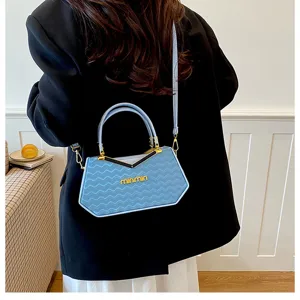 Dettaglio borsa a tracolla azzurra con motivo a onde e manico in metallo elegante.