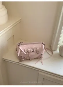 Roze glanzende cilindrische schoudertas met retro moto-hardware en gedetailleerde ritsen.