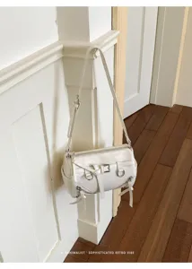 Gedetailleerd shot van een stijlvolle witte cilindrische schoudertas met retro bandjes.