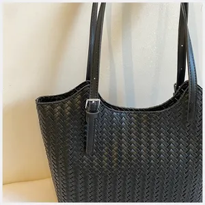 Vista di dettaglio di una borsa in pelle intrecciata nera con texture fine e fibbia.