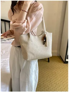 Dettaglio borsa a spalla intrecciata chic, elegante design in ecopelle beige con ciondolo.