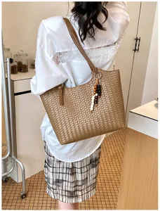 Vista dettagliata della borsa a spalla intrecciata elegante con ciondolo in scena interna.