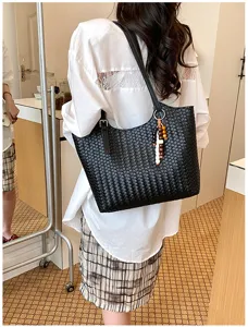 Vista dettagliata di una elegante borsa a spalla intrecciata nera indossata al chiuso.