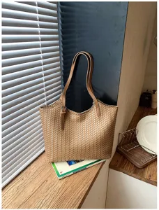 Vista dettagliata della texture della borsa tote in pelle intrecciata marrone con i doppi manici.