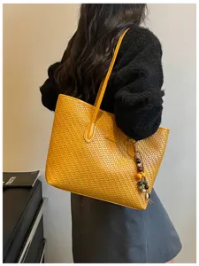 Sac cabas tressé en cuir jaune élégant avec charm perlé, idéal pour le quotidien chic.