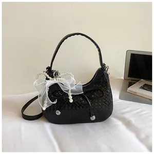 Detailed view of black woven crescent bag with pearl bow, elegant texture design.