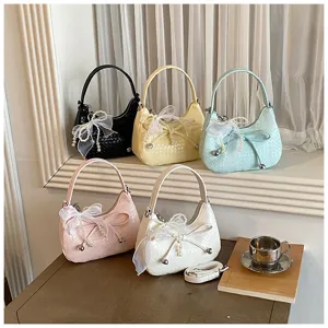 Detailed view of fashionable woven crescent bags with pearl bow, chic underarm and crossbody style.