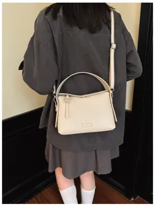 Detailed view of casual beige leather crossbody bag, stylish top handle design for everyday wear.
