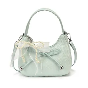 Mint green woven crescent shoulder bag with pearl bow, stylish underarm bag for women.