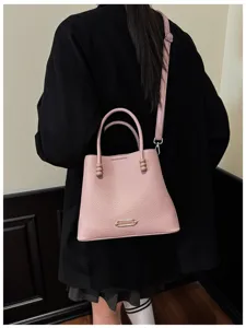 Detailed view of the pink leather bucket bag, showing the metal logo plate and handle bead decor.