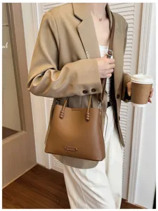 Brown leather bucket bag with top handle and shoulder strap for women daily commute style.