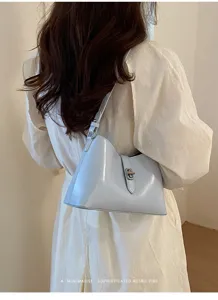 Dettaglio di borsa a spalla azzurra minimalista con chiusura a girello in metallo.