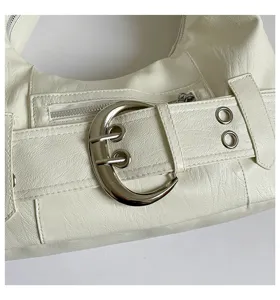 White faux leather shoulder bag detail, featuring large metal buckle and grommet decoration.