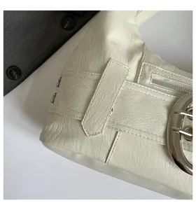 Close-up detail of cream white leather shoulder bag with metal buckle and zipper accent.