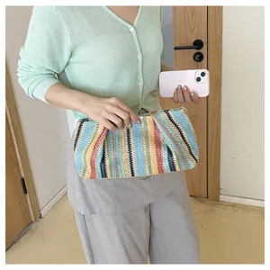 Detailed view of a colorful striped woven clutch bag, straw pouch for summer beach vacation style.