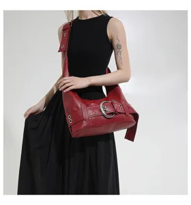 Red faux leather shoulder bag with metal buckle and grommet details for daily wear.