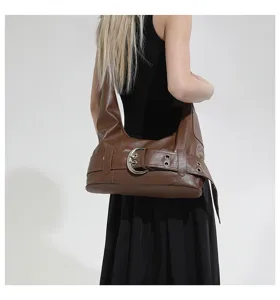 Brown leather hobo shoulder bag with silver buckle strap detail, trendy Y2K motorcycle style.