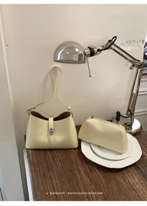 Primo piano della borsa a spalla minimalista giallo crema con elegante chiusura in metallo.