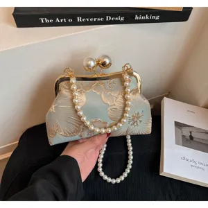 Λεπτομέρεια vintage κεντητής τσάντας clutch με λουλούδια και κομψή λαβή από πέρλες.