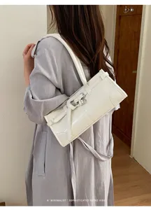 Vista dettagliata della borsa a spalla bianca minimalista con elegante fibbia e design retrò in pelle.