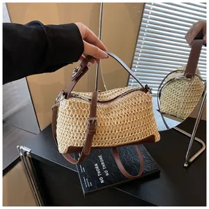 Vue de détail rapprochée de la texture du sac en paille tressée, lanière en cuir marron.