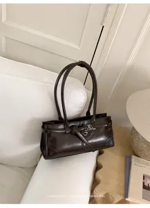 Dettaglio borsa a spalla retrò in pelle marrone scuro, elegante fibbia con anello.