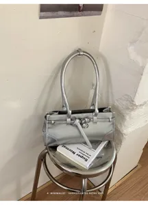 Dettaglio borsa a spalla metallizzata argentata, design minimalista moderno con anello in metallo.