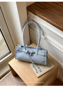 Dettaglio della borsa a spalla in pelle azzurra con fibbia metallica e manico lungo.