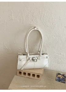 Dettaglio borsa a spalla minimalista bianca con pelle pregiata e fibbia metallica.