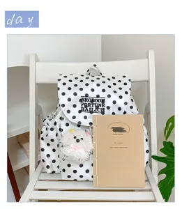 Stylish black and white polka dot backpack with cute plush pendant for daily casual wear.