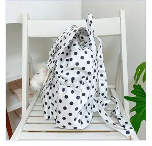 Detail view of a stylish black and white polka dot backpack featuring drawstring and flap closure.