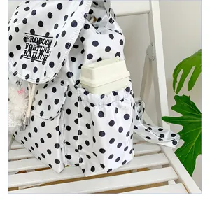 Detailed view of fashionable white backpack with black polka dots, featuring front pocket and drawstrings.