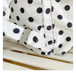 Close-up detail of white backpack with black polka dots and metal buckle strap adjuster.