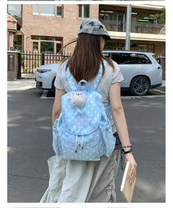 Backpack detail view showing cute plush charm pendant, polka dot pattern and stylish embroidery.