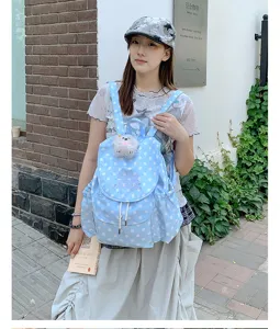Chic light blue polka dot backpack with cute plush pendant, stylish casual daily daypack.