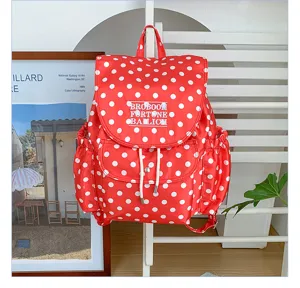 Detail shot of a stylish red and white polka dot backpack with drawstring and front pocket.