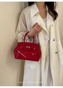 Detailed shot of the red leather handbag with metallic turn-lock and front zipper pocket.