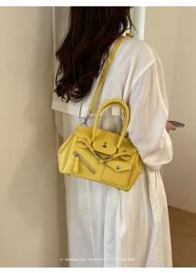 Yellow leather top handle shoulder bag detail shot, minimalist retro style fashion accessory.