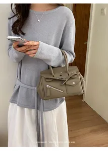 Stylish grey leather handbag featuring unique zipped pocket and classic turn-lock design.